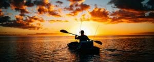 a man kayaking i nthe sunset