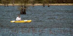 a kayaker checking his fishing rod in a lake