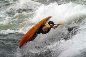 a man doing kayak tricks in the rapids